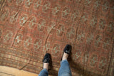 Distressed Afghan Bokhara carpet displaying geometric guls and subtle chestnut and silver hues.