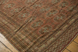 Distressed Bokhara rug: geometric elephant footprint guls, striped border, chestnut and muted tones.