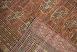 Distressed Bokhara rug folded corner, showcasing low pile and intricate woven reverse.