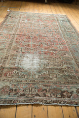 Distressed vintage Mehrivan carpet end with fringed edge, muted colors, and rectilinear patterns.