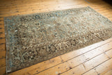 Distressed Mehrivan rug corner with geometric patterns in sandy beige, brown, and muted blue.