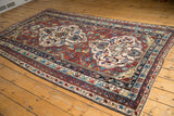 Wine red field, ivory medallion motif, and geometric multi-hued borders on the antique Shirvan carpet.