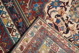 Antique Shirvan carpet's folded corner, showcasing hand-knotted construction, red, blue, ivory patterns.