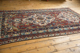 Angled view of antique Shirvan carpet's wine red field, sky blue medallion, and visible foundation.
