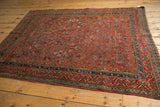 Cherry red geometric floral motifs and navy blue border detail on vintage Qashqai rug corner.