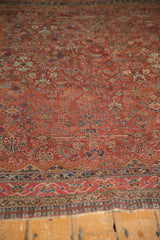Vintage Qashqai rug's cherry red field, intricate geometric floral motifs, navy border, and fringe.