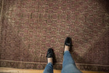 Distressed Malayer rug close-up showing repeating booths, vinery, and soft raspberry, mauve, ivory tones.