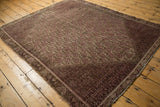 Distressed vintage Malayer rug corner, with faded raspberry red and coffee brown geometric border.