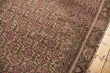 Distressed corner of the vintage Malayer rug showing pale raspberry booths and exposed foundation.