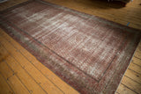 Distressed antique Mir Serbend carpet corner reveals textural wear, muted red field, and intricate border details.