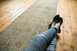 Distressed vintage Hamadan runner showing faded teal, ivory, and bronze medallions with even wear.