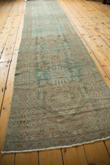 Distressed vintage Hamadan runner's fringed end, with faded teal and bronze patterns.