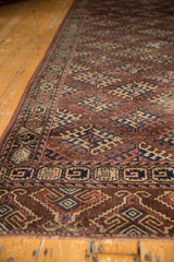 Secured end of the antique Turkmen rug, showing geometric aubergine, navy, and ivory border.
