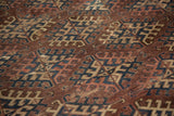 Geometric hook gul motifs on antique Turkmen carpet in aubergine, navy, ivory, showing wear.
