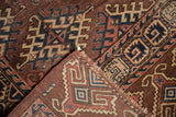 Antique Turkmen rug corner showing geometric hook gul motifs and aubergine, navy border.