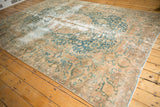 Distressed texture of a vintage Kashmar rug, with teal floral motifs and exposed foundation.