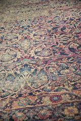 Patina-rich texture of elaborately drawn scrolling vines in navy, cochineal, and antique ivory.