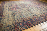 Vintage Persian Yezd carpet detail: intricate scrolling vines, floral border, time-softened navy, cochineal.