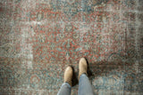 Distressed vintage Kashan rug's faded blush red, sky blue floral pattern, with visible foundation.