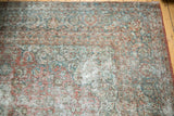 Distressed vintage Kashan rug corner, faded floral patterns, visible foundation.