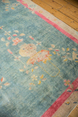 Worn aqua blue Art Deco carpet corner with faded floral motifs and bright pink border.