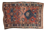 Antique hand-knotted Caucasian rug with asymmetric geometric patterns in brick red, navy blue, ivory.