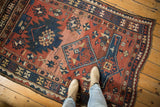 Antique Caucasian geometric rug detail: oversized brick red, navy, ivory motifs, low pile wear.
