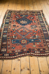 Antique Caucasian rug detail: playful geometric patterns, brick red, navy, ivory, and low pile.
