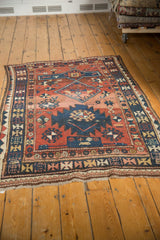 Worn woven fringe and geometric navy, brick red, ivory border of the antique Caucasian rug.