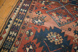 Geometric patterns and low pile wear on an antique Caucasian rug close-up.