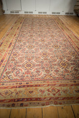 Angled view of antique Malayer runner, displaying distressed Herati pattern in ivory, rust, and pale green.