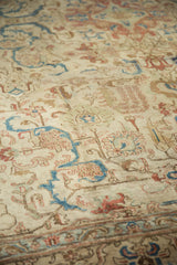 Distressed ivory field of a vintage Tabriz rug with faded blue and terra cotta tendrils.