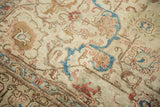 Distressed pile of vintage Tabriz rug with soft ivory, sky blue, and terra cotta motifs.