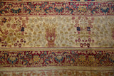 Antique Kermanshah carpet detail with ivory mille fleur field, cochineal red floral border, and knot heads.