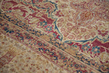 Close-up of hand-knotted antique Kermanshah rug, mil fleur pattern, border in red, blue, ivory, visible wear.
