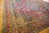 Intricate corner of an Antique Kerman carpet featuring plum red, navy floral vinery, and ornate borders.