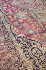 Curvilinear mille fleur floral pattern in plum, cochineal red, and navy on antique Kerman.