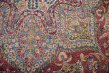 Plum red, powder blue, ivory low pile on an antique Kerman rug's scrolling vinery.
