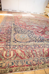 Antique Kerman carpet, cochineal red field with scrolling vinery, navy borders, and antique ivory patterns.