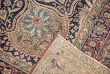Antique Kerman rug's folded corner, showing rich plum, navy, beige floral motifs and woven back.