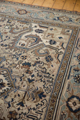 Distressed vintage Heriz carpet section with geometric vinery and soft blue, brown hues.