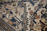 Distressed vintage Heriz rug detail: worn geometric vinery in beige, navy, and coffee brown.