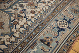 Intricate geometric vinery in antique ivory, powder blue, and brown on a distressed Heriz carpet.