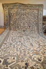 Unfurled large vintage Heriz carpet, showcasing distressed texture and geometric ivory-blue design.