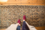 Distressed Sarouk runner with beige field and muted floral motifs, showing mostly even wear.