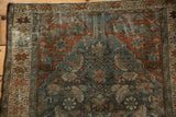 Distressed vintage Hamadan rug corner, revealing dusty teal Herati motif, burgundy field, and textured wear.