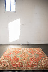 Distressed vintage Heriz rug with geometric medallion and floral palmettes in red and teal.