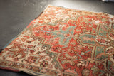 Close-up of a distressed Heriz rug showing cherry red, teal, and ivory geometric floral motifs.