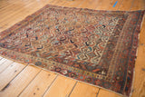 Corner of antique Afshar rug showing rectilinear geometric motifs and madder root red border with wear.