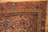 Worn corner of antique Afshar rug with madder red, ivory, blue geometric border details.